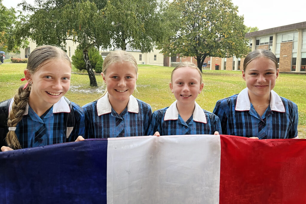 Four french students hold up the French flag at school