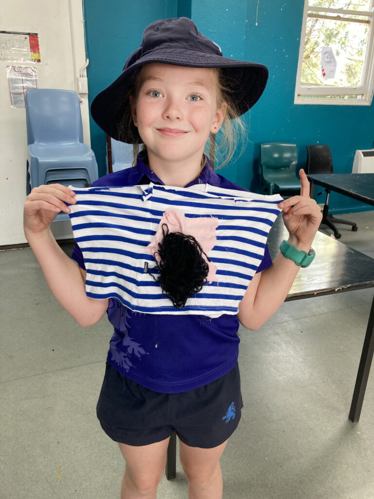 Primary school student displaying their art clothing piece inspired by waste 